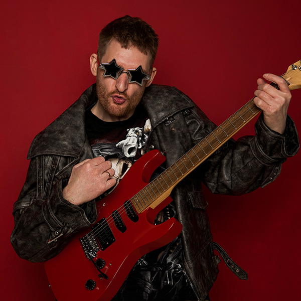 Donatas su raudona gitara ir žvaigždės formos akiniais